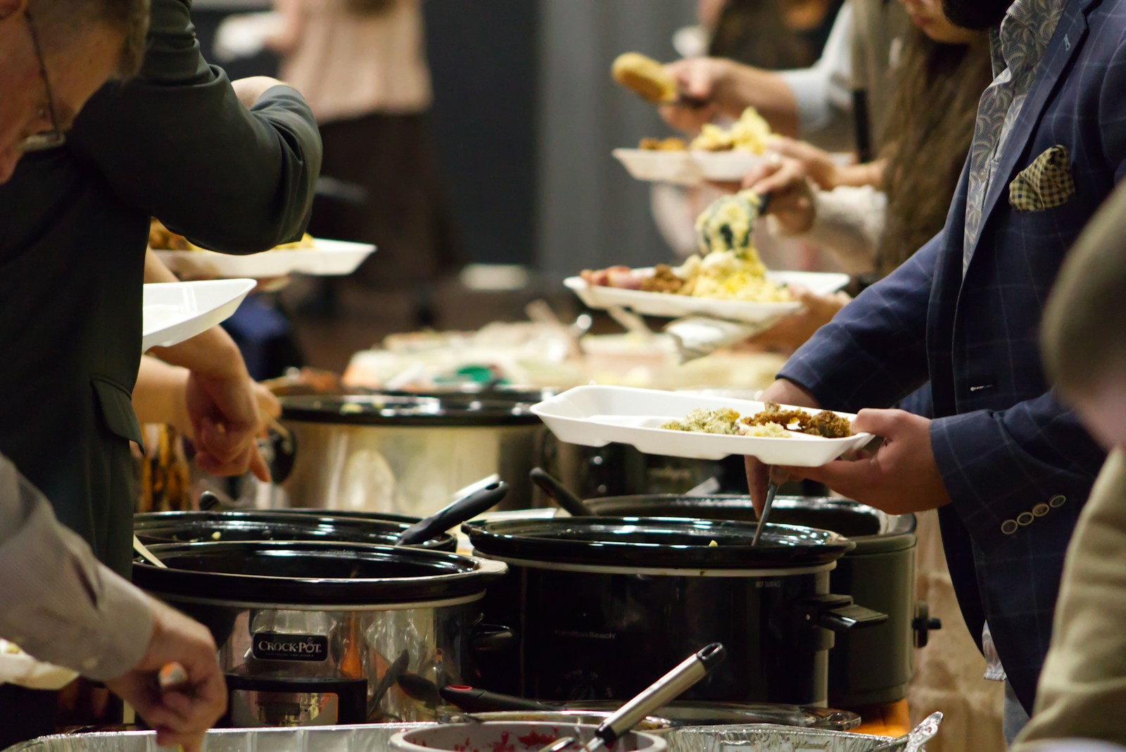 Photo by Jacob McGowin A group of people standing around a buffet line